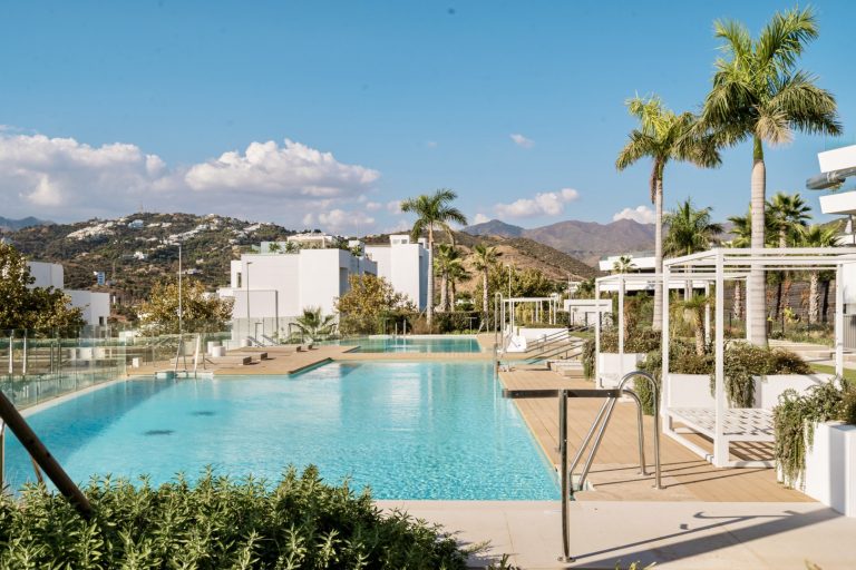 Modern communal swimming pool at Soul Marbella with sun loungers and landscaped gardens